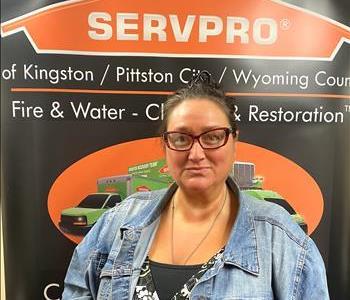 Female Administrative Assistant in front of SERVPRO black and orange pop up sign