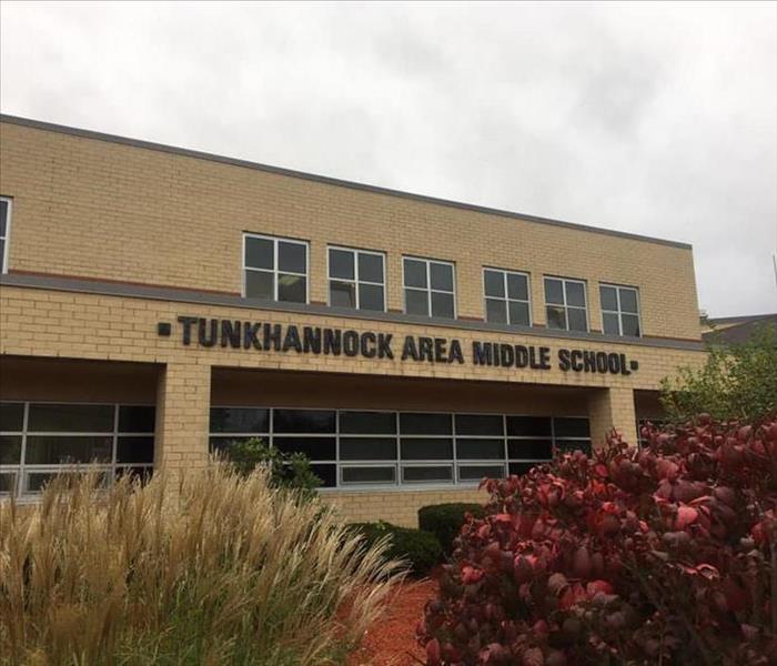Brick building with text that says "Tunkhannock Area Middle School" and bushes in front of it.