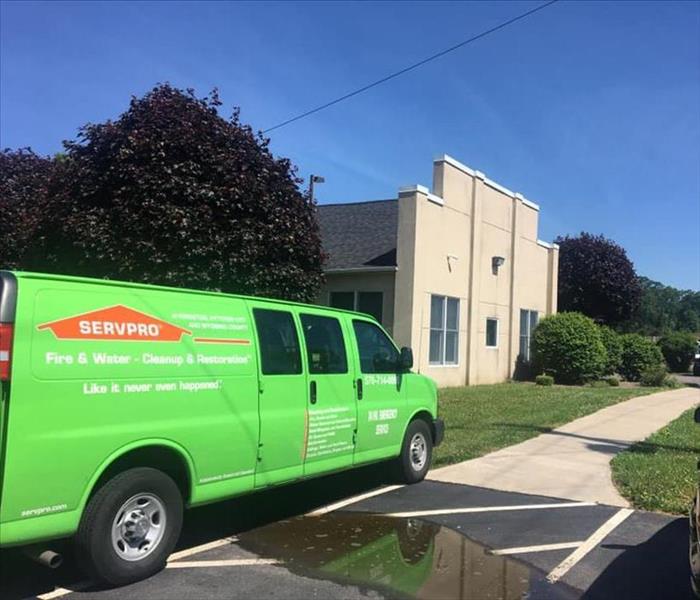 Green SERVPRO truck in front of tan building