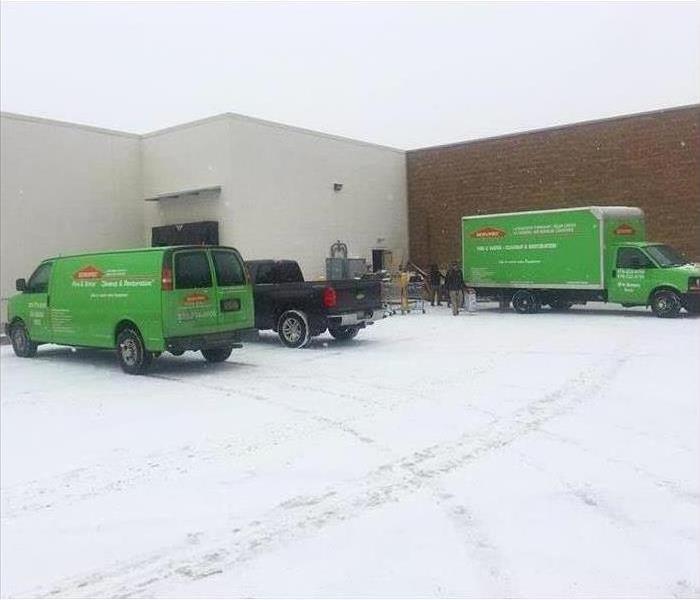 three SERVPRO trucks in front of commercial building in the snow