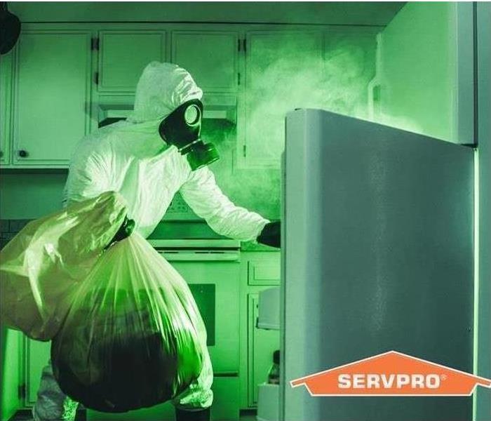 SERVPRO tech in PPE removing biohazard items 