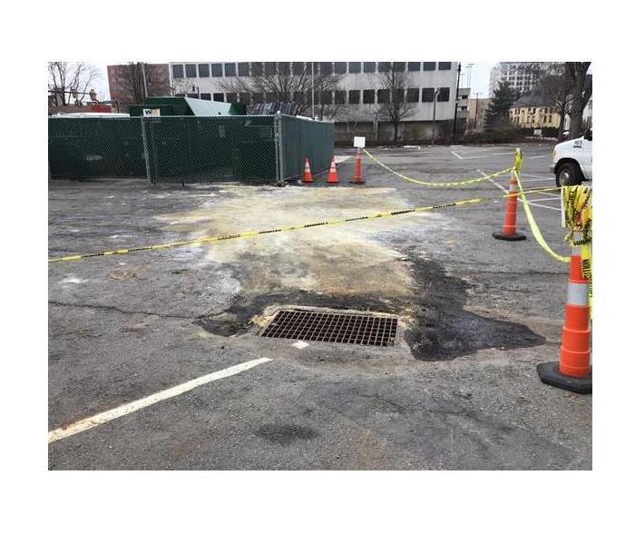 oil spilled on blacktop parking lot with garbage can 
